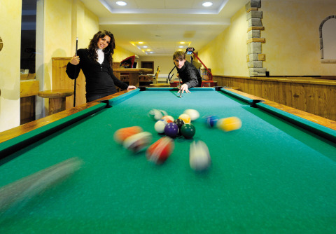 Twee mensen spelen biljart in Camping Seeblick Toni in Tirol, Oostenrijk. Ballen verspreiden zich op tafel.