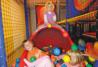 Kinder spielen im Bällebad und auf einer Rutsche im Camping Seeblick Toni, einem Ferienpark in Tirol, Österreich.