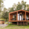 Lakehouse-lodge met houten terras en hottub buiten, omringd door bomen en natuur.