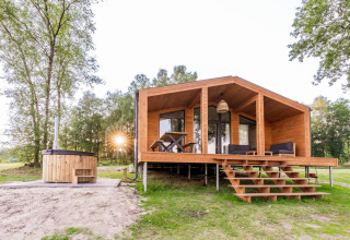 Cabaña de madera con terraza y jacuzzi exterior en Lakehouse Wilsumer Berge, rodeada de naturaleza, Alemania.