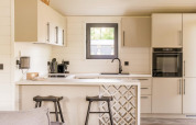 Cuisine moderne au Lakehouse + hottub à Wilsumer Berge, Allemagne, avec tabourets et décor lumineux.