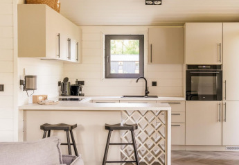 Cuisine moderne au Lakehouse + hottub à Wilsumer Berge, Allemagne, avec tabourets et décor lumineux.