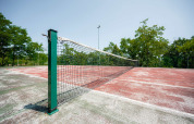 Pista de tenis al aire libre con superficie roja desgastada en Camping Centro Vacanze San Marino, Italia.