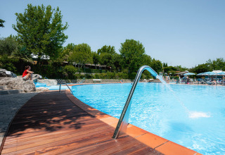 Piscina all'aperto con bordo in legno e alberi verdi al Camping Centro Vacanze San Marino, Italia.