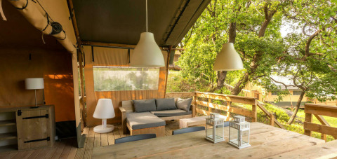 Salon extérieur avec mobilier en bois et luminaires, entouré de verdure au Camping Centro Vacanze San Marino, Italie.
