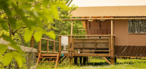 Tente safari sur terrasse en bois au Camping Centro Vacanze San Marino, entourée de verdure et de fleurs.