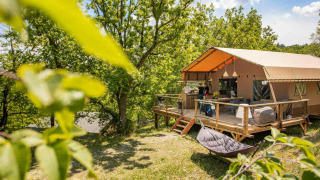 Glamping tent at Camping Centro Vacanze San Marino surrounded by greenery and natural forest setting.