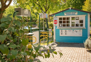 Ingresso piscina del Camping Centro Vacanze San Marino in Italia, con casetta dei biglietti e tornelli gialli.