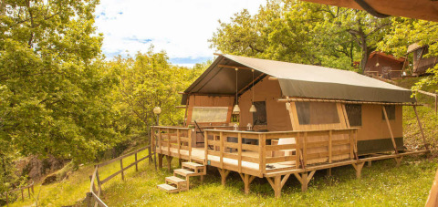 Safari tent with raised wooden deck in lush greenery at Camping Centro Vacanze San Marino in Italy.