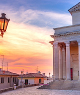 Sunset over historic buildings and a classical church near Cailungo, San Marino, Italy.