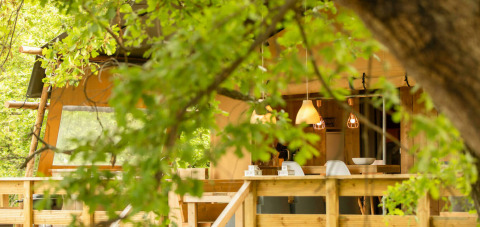 Vista exterior de la tienda safari Desert Lodge en Camping Centro Vacanze San Marino, Italia, rodeada de árboles.