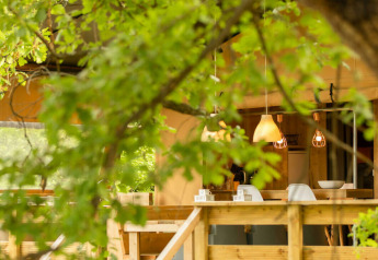 Vista esterna della tenda safari Desert Lodge al Camping Centro Vacanze San Marino, Italia, tra gli alberi verdi.