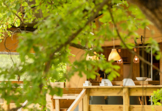 Vista exterior de la tienda safari Desert Lodge en Camping Centro Vacanze San Marino, Italia, rodeada de árboles.