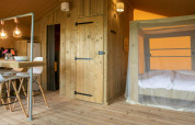 Interior de la tienda safari Desert Lodge en Camping Centro Vacanze San Marino con comedor y cama acogedora.