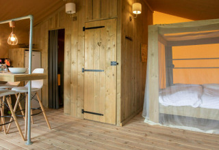 Interior de la tienda safari Desert Lodge en Camping Centro Vacanze San Marino con comedor y cama acogedora.