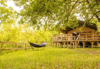 Safaritent Desert Lodge met houten terras en hangmat in het groen bij Camping Centro Vacanze San Marino.