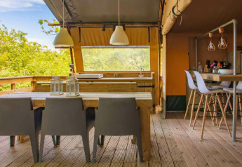 Zona de comedor exterior y cocina en la tienda Safari Desert Lodge en Camping Centro Vacanze San Marino, Italia.