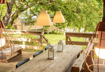 Zona pranzo esterna con tavolo in legno e lampade sospese alla tenda Desert Lodge del Camping San Marino, Italia.