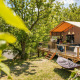 Safari-telt Desert Lodge + sanitaire med træterrasse midt i naturen, omgivet af grønne træer og planter.