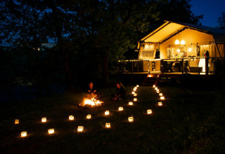 Vista nocturna de la tienda safari Desert Lodge en Camping Centro Vacanze San Marino, Italia, con faroles.