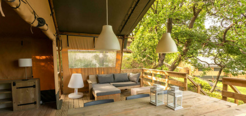 Desert Lodge safari tent with wooden deck, dining area and lounge at Camping Centro Vacanze San Marino, Italy.