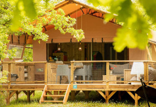 Ampia tenda safari con veranda in legno al Camping Centro Vacanze San Marino, Italia, immersa nel verde.