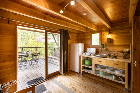 Interior view of a cozy wooden cabin with small kitchen and terrace at Cahutte glamping accommodation.