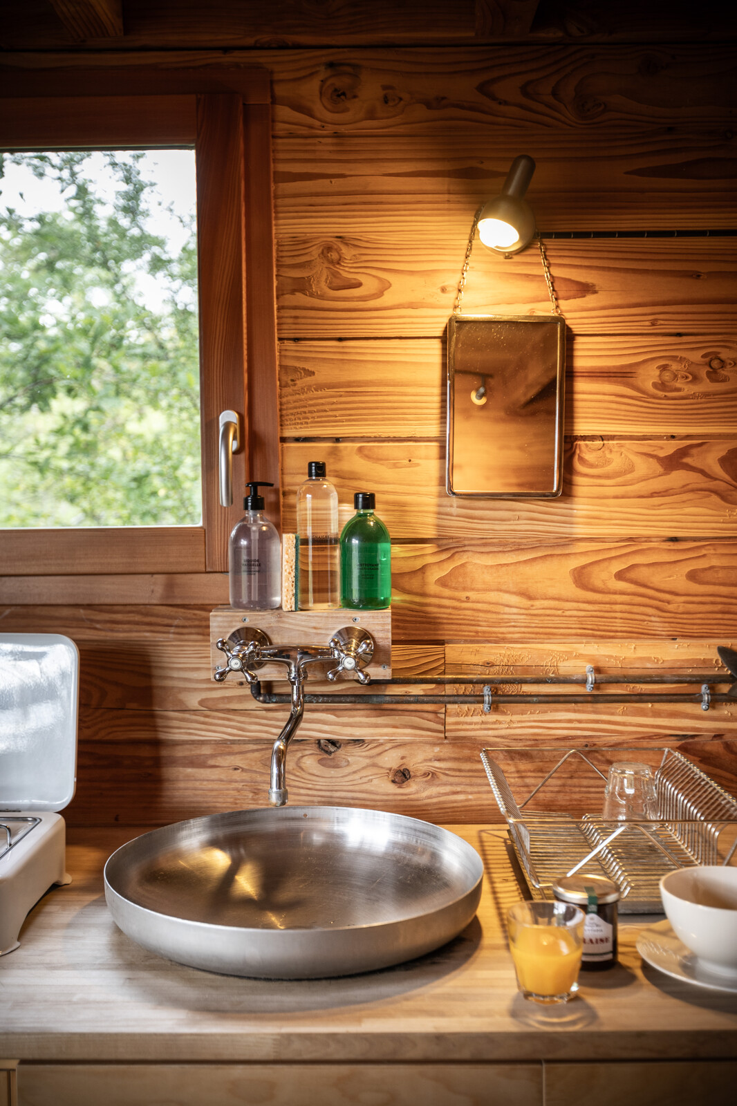 Gezellige keukenhoek in een Cahutte glampingaccommodatie met houten wand, ronde wasbak en raam.