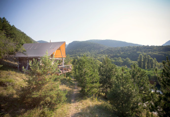 Una tenda safari Cahutte al Village Huttopia Dieulefit in Francia, immersa tra pini e dolci colline verdi.