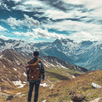 Un senderista con mochila contempla las montañas cerca de Sachsenburg, Carintia, Austria, bajo un cielo dramático.