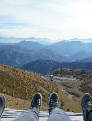 Pies con botas contemplan un paisaje montañoso cerca de Sachsenburg en Carintia, Austria.