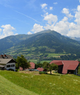 Paisaje pintoresco de granjas, prados verdes y montañas cerca de Sachsenburg, Carintia, Austria en día soleado.