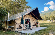 Vrouw geniet op het terras van een safari Trappeur-tent in Huttopia Vallouise, Frankrijk, tussen de natuur.