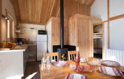 Indvendig af Chalet Montana ved Huttopia Vallouise i Frankrig med køkken, spisebord og brændeovn.
