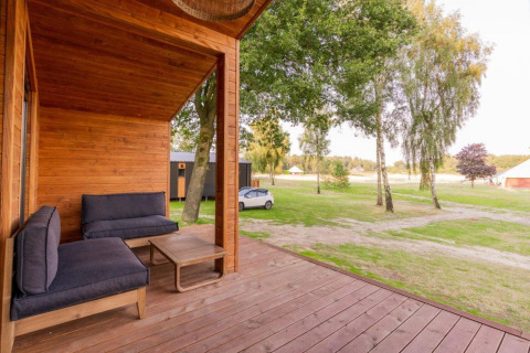 Træterrasse på Lakehouse med moderne sofaer og udsigt til grønne træer ved Wilsumer Berge, Tyskland.