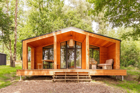 Houten lodge in Scandinavische stijl bij Forresthouse Scandi, Wilsumer Berge, Duitsland, omgeven door bos.