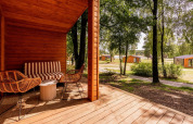 Zicht vanop de veranda van Forresthouse Scandi in Wilsumer Berge, Duitsland, met houten chalets in het groen.