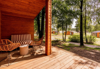 Zicht vanop de veranda van Forresthouse Scandi in Wilsumer Berge, Duitsland, met houten chalets in het groen.