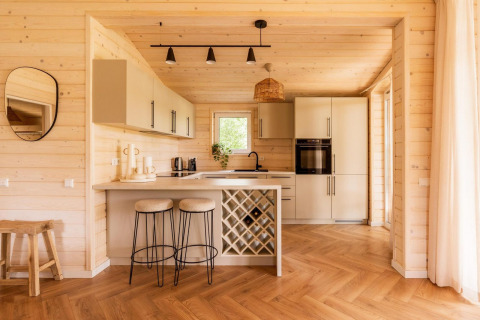 Modern Scandinavisch houten keukeninterieur met barkrukken en wijnrek in Forresthouse Scandi lodge.