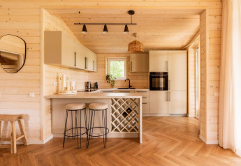 Modern Scandinavisch houten keukeninterieur met barkrukken en wijnrek in Forresthouse Scandi lodge.