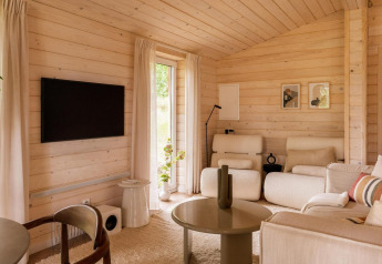Lichte Scandinavische leefruimte in Forresthouse Scandi, Wilsumer Berge, Duitsland, met houten panelen en hedendaags interieur.