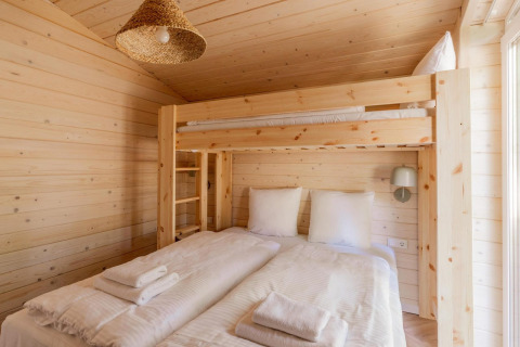 Lichte houten kamer met stapelbed boven tweepersoonsbed in Forresthouse Scandi, Wilsumer Berge, Duitsland.