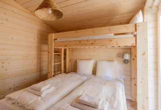 Habitación de madera clara con litera sobre cama doble en Forresthouse Scandi, Wilsumer Berge, Alemania.
