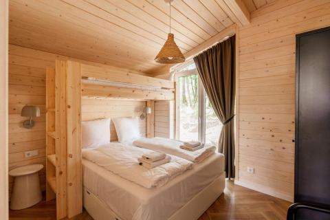 Slaapkamer in Forresthouse Scandi, Wilsumer Berge, Duitsland, met tweepersoonsbed, stapelbed en houten wanden.