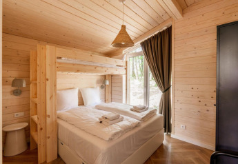 Slaapkamer in Forresthouse Scandi, Wilsumer Berge, Duitsland, met dubbel bed, stapelbed en houten bekleding.