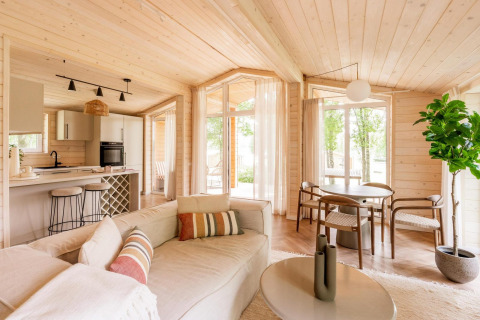 Interior luminoso y moderno de lodge en Forresthouse Scandi, Wilsumer Berge, Alemania, con paneles de madera y ventanales.