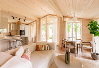 Interior luminoso y moderno de lodge en Forresthouse Scandi, Wilsumer Berge, Alemania, con paneles de madera y ventanales.
