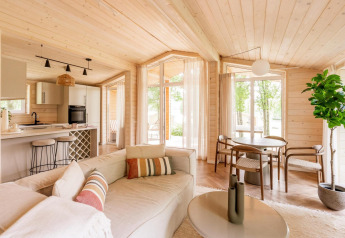 Intérieur moderne et lumineux d’un lodge du Forresthouse Scandi à Wilsumer Berge, avec boiseries et grandes fenêtres.