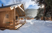 Wooden chalet cabins surrounded by snowy landscape at Les chalets Huttopia de Bourg-St-Maurice, France
