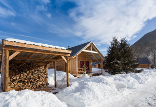 Sneeuwbedekte houten chalets en een houthok bij Les chalets Huttopia de Bourg-St-Maurice in Frankrijk.